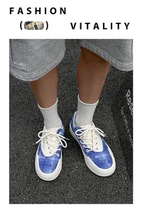 Draufsicht auf stylische blau-weiß gemusterte Low-Top-Canvas-Sneaker auf Asphalt