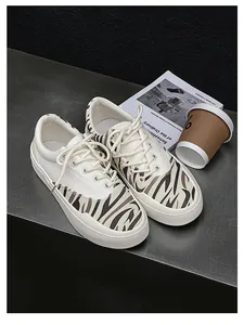 Detailansicht weißer Canvas-Sneaker mit modischen Zebrastreifen-Akzenten auf dunklem Grund.