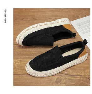 Close-up of black breathable linen loafers with woven espadrille soles on wood
