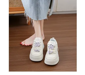 Close-up detail of women's chunky platform white sneakers with cute purple cartoon charms