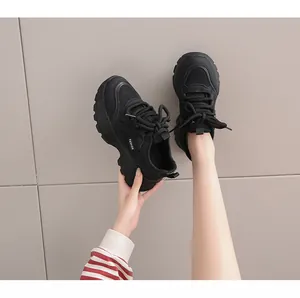 Detailed view of black chunky sneakers featuring mesh panels, synthetic leather, and thick laces.