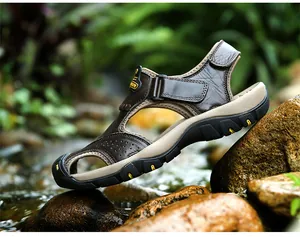 Detailed side view of brown leather closed-toe outdoor sandals on river rocks
