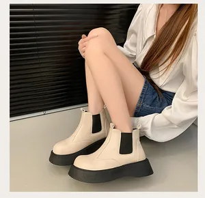 Close-up look of chic beige platform Chelsea boots worn by a model in a studio setting