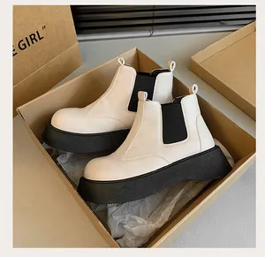 Detailed view of white platform Martin boots with thick black soles inside a shoe box