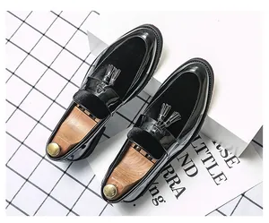 Macro view of black patent leather loafers with decorative tassels and wood shoe trees