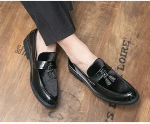 Close-up of men's black patent leather loafers with tassels and velvet panels.
