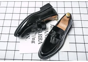 Detailed view of men's black patent leather loafers with tassels and velvet texture