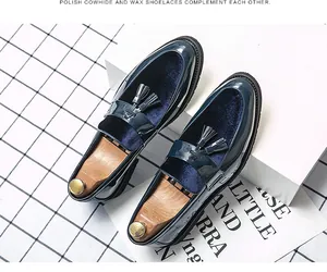 Close-up of elegant polished blue leather and velvet tassel loafers with wooden shoe trees.