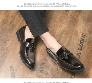 Detail view of men's patent leather tassel loafers on a rustic wooden floor