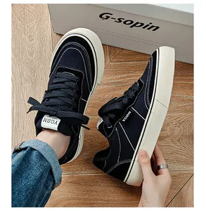 Detail view of men's low-top black canvas sneakers with vulcanized soles.