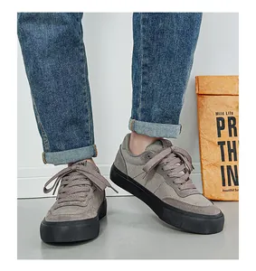 Close-up of men's grey low-top canvas sneakers featuring black vulcanized soles and matching laces