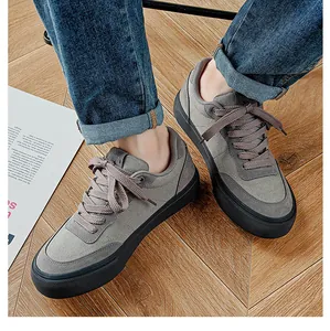 Close-up of men's low-top gray canvas shoes with black vulcanized soles on wooden floor