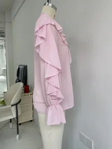 Elegant pink chiffon blouse featuring ruffled long sleeves and bell cuffs on mannequin