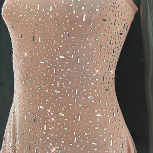 Detailed view of sparkling rhinestones on a nude semi-transparent mesh party mini dress.
