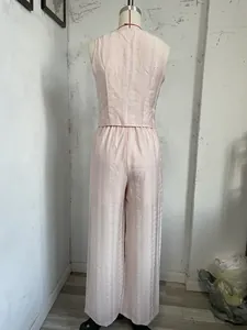 Rückansicht von rosa ärmelloser Weste und Hose mit weitem Bein und weißer Stickerei.