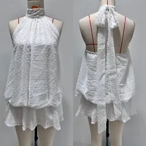 Vue détaillée du licou dos nu et de la texture à pois sur cette élégante robe blanche.