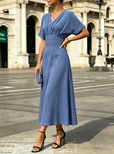 Close-up of a elegant blue V-neck midi dress with pleated waist detail in sunlight