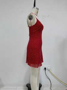 Side profile detail of a red sleeveless mini dress with white polka dots on a mannequin