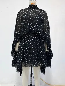 Vooraanzicht van een elegante zwarte chiffon jurk met stippen en slip op een paspop