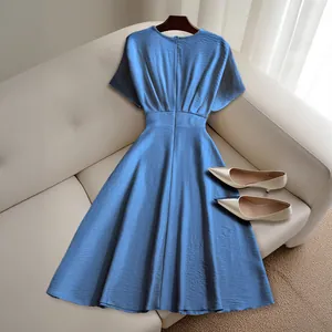 Elegant blue short-sleeved midi dress with a cinched waist on a white sofa