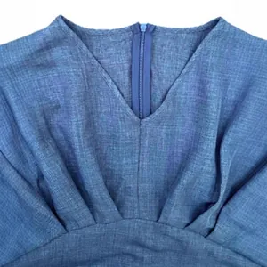 Close-up detail of V-neckline and gathered waist on a blue linen-textured dress.