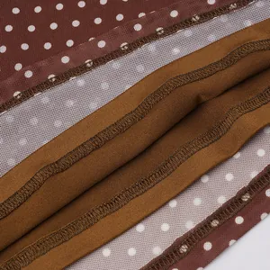 Detailed macro view showing the overlock stitching and mesh of a brown polka dot dress