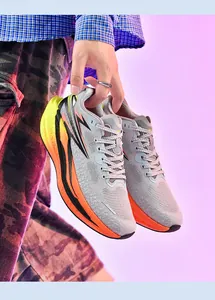 Nahaufnahme von stilvollen grau-orangen Laufschuhen mit Schnürung, die man in der Hand hält