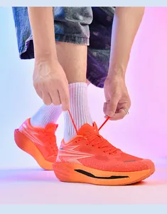 Detailansicht von leuchtend orangefarbenen Laufschuhen beim Binden der Schnürsenkel.