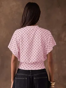 Back view of a pink polka dot blouse with retro batwing sleeves and a cinched waist.