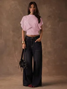 Full view of a pink polka dot batwing sleeve top with high-waisted wide-leg jeans.