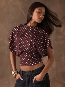 Detailed professional view of a burgundy polka dot cropped top with elegant batwing sleeves