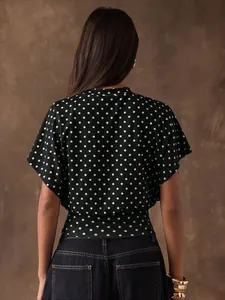 Rear view of a stylish retro black polka dot blouse featuring batwing sleeves and slim fit design