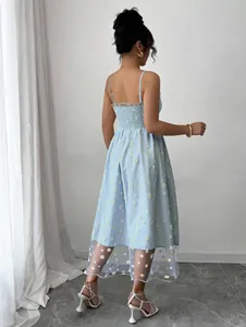 Back view of a light blue smocked daisy embroidery midi dress featuring a sheer mesh hem