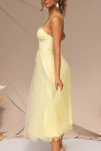 Detail shot of a yellow tulle spaghetti strap dress showing silhouette and fabric.