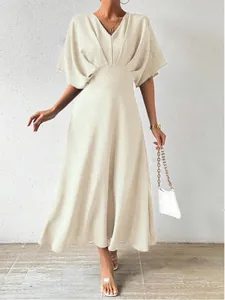 Elegant V-neck cinched waist midi dress in beige styled with a white chain handbag