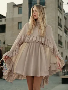 Detailweergave van een gelaagde chiffonjurk met ruches cape in een elegant beige
