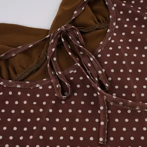 Close-up detail of brown polka dot dress with mesh fabric and adjustable tie neckline.