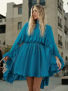 Volledig zicht op de blauwe chiffon jurk met gelaagde ruches en vloeiend silhouet.