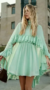 Elegante mintgroene chiffonjurk met ruches en cape-mouwen aan een modepopje