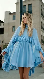 Detail van een blauwe chiffon jurk met prachtige gelaagde ruches en zwierige cape.