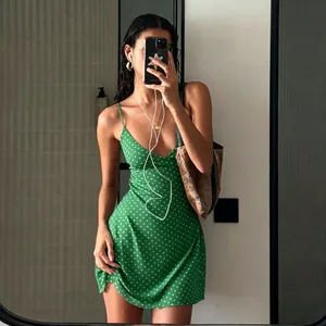 Mirror selfie showing the perfect fit of a vibrant green polka dot sleeveless slip mini dress.