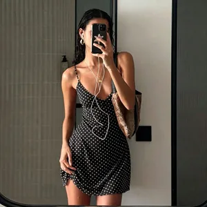 A stylish mirror selfie detailing a black sleeveless mini dress with white polka dots