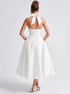 Detailed back view of an elegant white jacquard halter dress featuring a bow and lace-up design