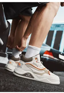 Sneakers alte da uomo alla moda con suola spessa e accenti arancioni vivaci.