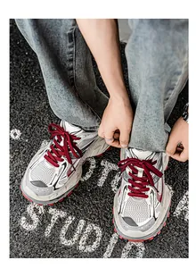 Top view detail of stylish men's chunky sneakers with red laces on textured asphalt