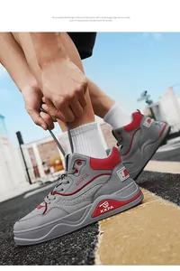 Primo piano dell'allacciatura di sneakers alte grigie e rosse in ambiente urbano