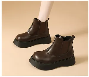 Close-up detail of dark brown platform Chelsea boots featuring front zipper and elastic panels