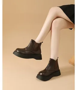 Detailed view of dark brown platform Chelsea boots featuring a front zipper on model