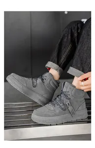Dettaglio di sneakers alte grigie da uomo con suole spesse e stile casual da strada.