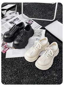 Detailweergave van de dikke plateau derby schoenen in Britse stijl in zwart en crème.